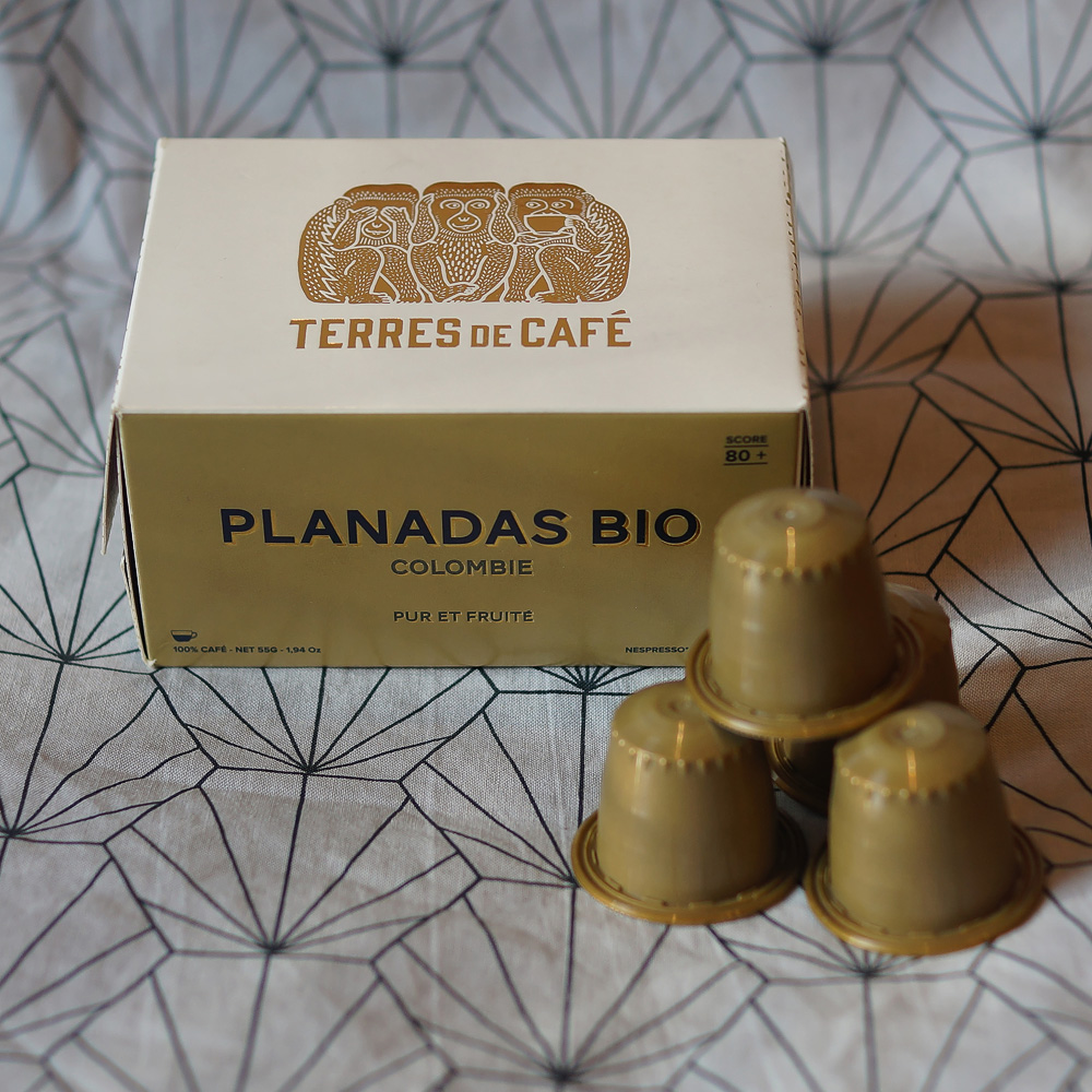Planadas Bio coffee capsules by Terres de Café - brown capsules with the box on a grey background