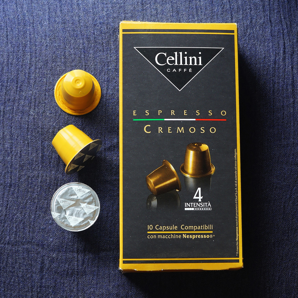 Cremoso by Cellini Caffee - Three yellow coffee capsules and the coffee box on a blue background