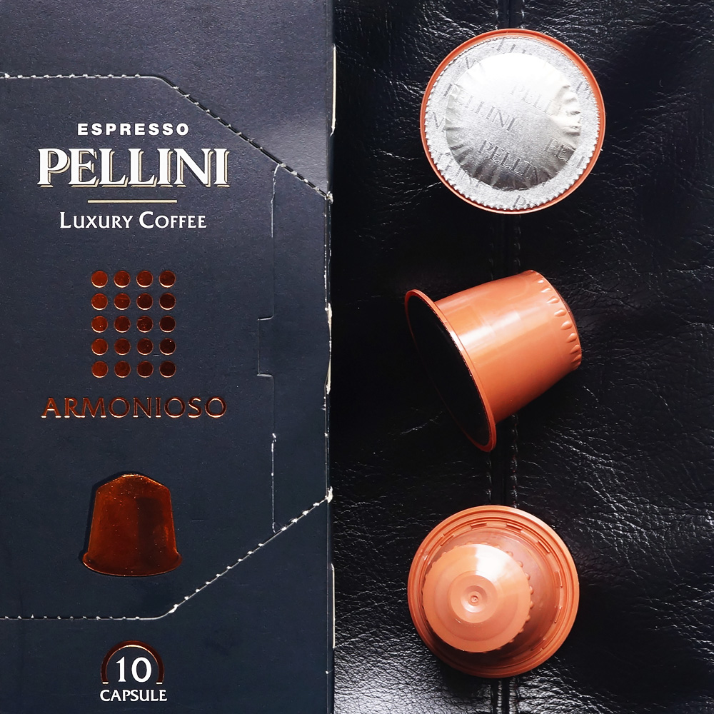 Armonioso by Pellini Espresso - three orange coffee capsules with the box on a black background