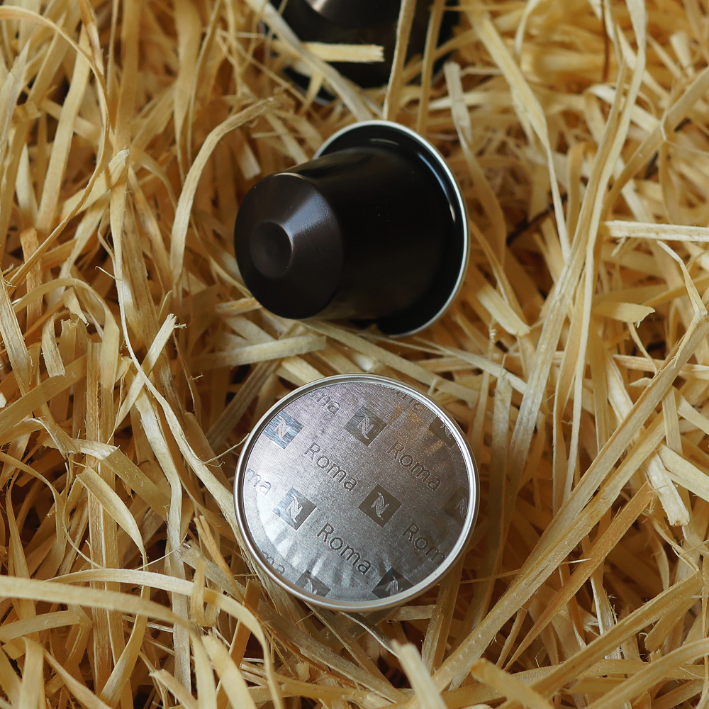 Roma by Nespresso - three black coffee capsules on hay