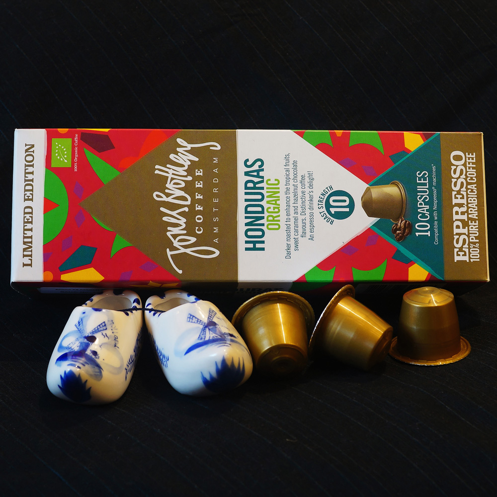 Organic Honduras - golden coffee capsules with the colourful box on a black background