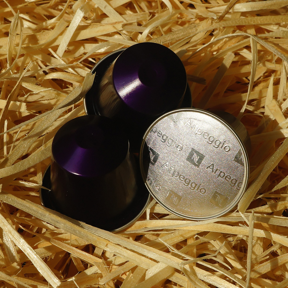 Arpeggio by Nespresso - three dark violet coffee capsules on hay