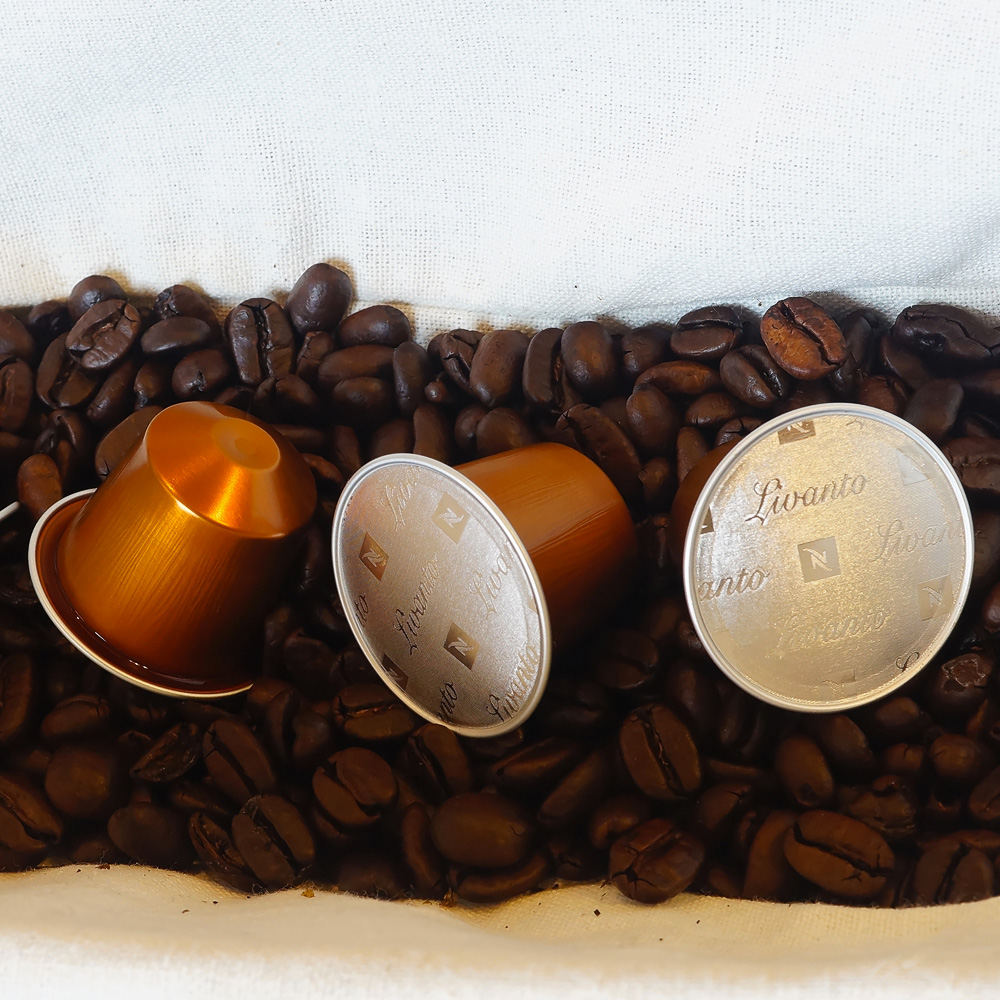 Livanto Nespresso - three orange coffee capsules on coffee bean background