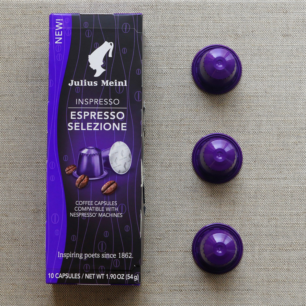 Espresso Selezione by Julius Meinl - three violette coffee capsules with a box on pale background