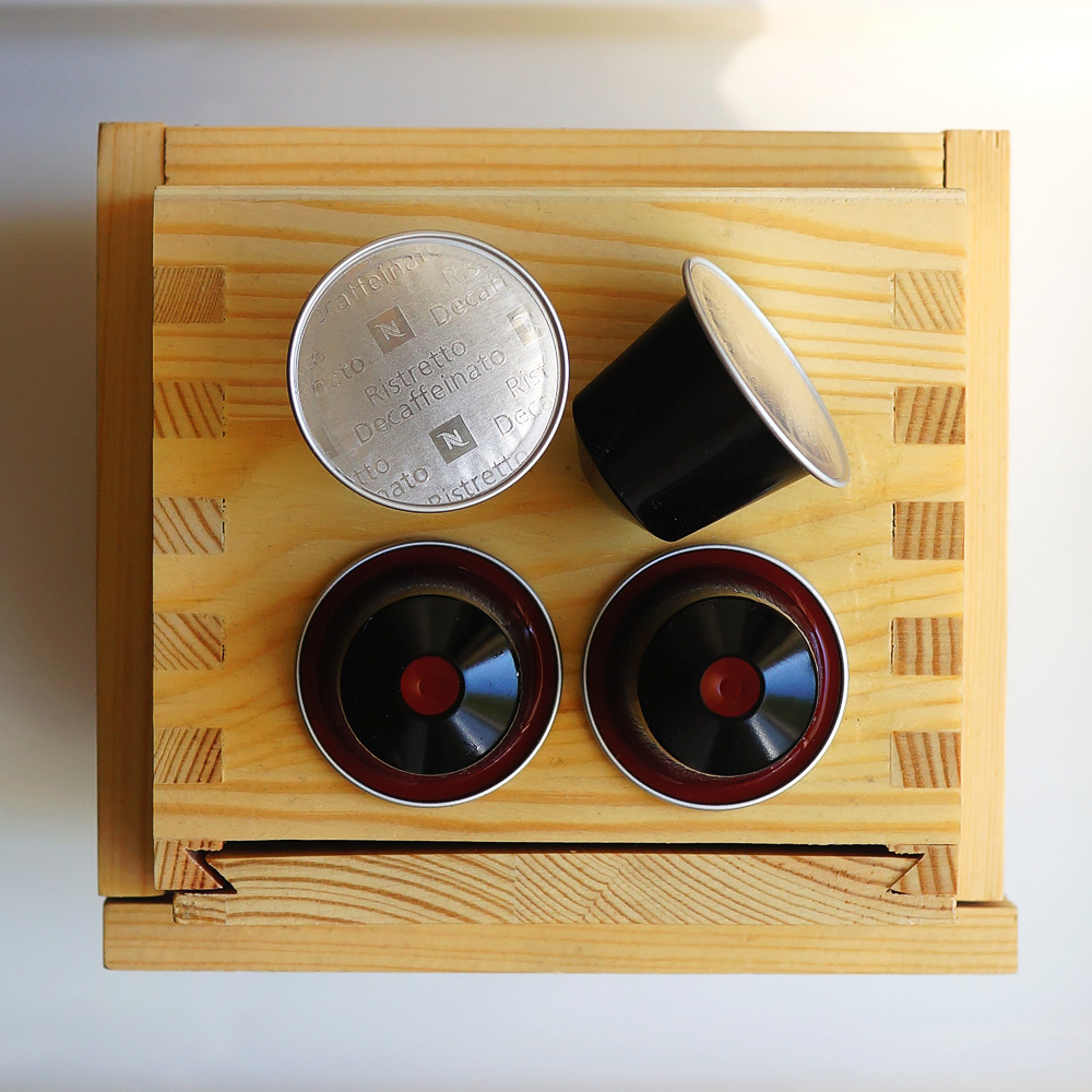 Ristretto Decaffeinato by Nespresso - four black coffee capsules on wooden background