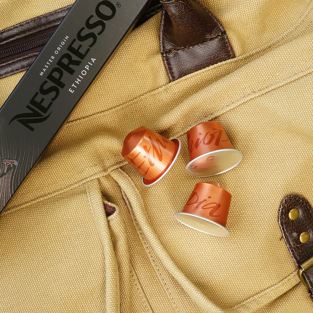 Three orange coffee capsules on a weekender bag